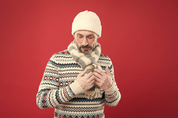 Winter collection. Warmth and comfort. Cold winter conditions. Handsome bearded man wearing hat and scarf red background. Winter sweater. Knitted accessories. Winter weather style. Menswear concept - Photo, Image