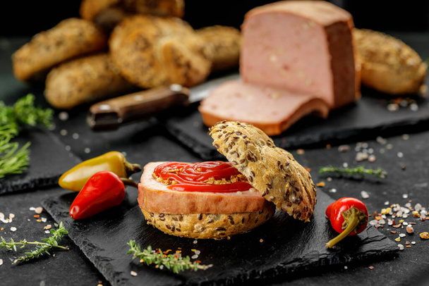 Stillleben-Komposition aus köstlichen Hot Dogs und Sandwiches mit verschiedenen Belägen und getrockneten Zwiebeln auf dunklem Hintergrund - Foto, Bild