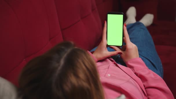 Cierra las manos de mujer sosteniendo el teléfono inteligente de pantalla verde cromakey viendo contenido, deslizando desplazamiento en el sofá en casa. Gadgets concepto de personas. - Metraje, vídeo