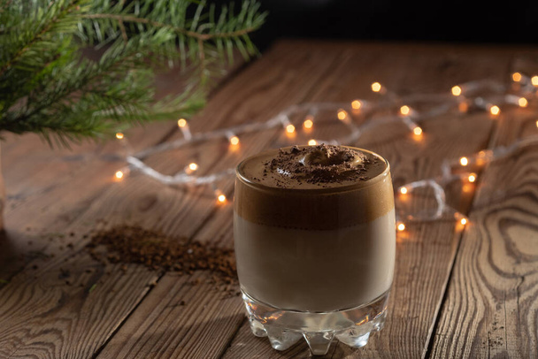 Um copo com café gelado Dalgona em uma atmosfera de Ano Novo, café chicoteado na moda com creme em uma mesa de madeira. - Foto, Imagem