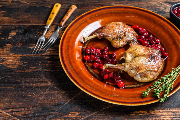 Roasted Christmas duck legs with cranberrie sauce. Dark wooden background. top view. Copy space. - Photo, Image