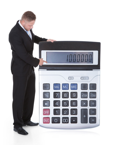 Smiling businessman displaying a calculator - Foto, afbeelding