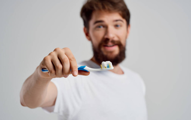 férfi egy fogkefével a kezében szájüreg ellátás reggeli eljárások hófehér mosoly fájdalom - Fotó, kép