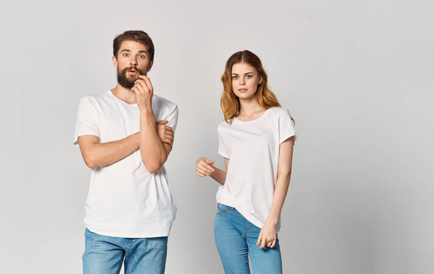 a man and a woman in jeans and a T-shirt on a light background gesturing with hands portrait friends family - Photo, Image