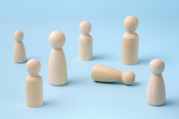 People gathering together to help person feeling bad or fainting. Person lying on the ground and people standing around. Wooden figurines concept. - Photo, Image