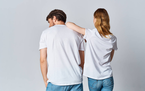 Un uomo e una donna con le stesse magliette e gli stessi jeans stanno gesticolando con le mani, retrovisore - Foto, immagini