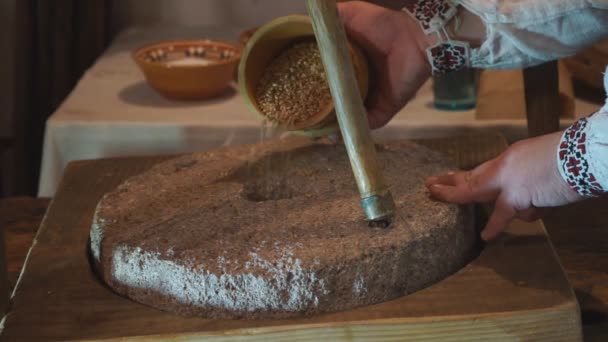 Versare il grano in un vecchio mulino. Miller versa i chicchi di grano in un mulino a pietra per fare la farina alla vecchia maniera - Filmati, video