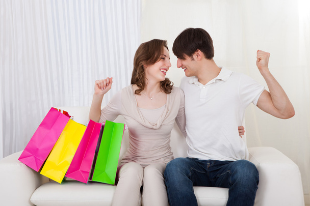 Happy couple sitting on couch with shopping bags - Foto, Imagen