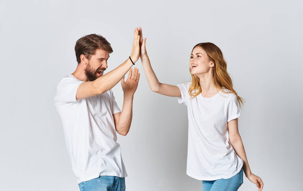 эмоциональный мужчина в футболке и женщина в джинсах на светлом фоне в стиле одежды одежды из ткани - Фото, изображение