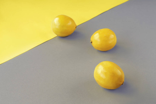 Lemons on yellow and gray background. Trendy colors 2021. Minimal composition, top view, copy space. - Фото, зображення