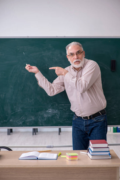 Old male teacher sitting in the classroom - Foto, Bild