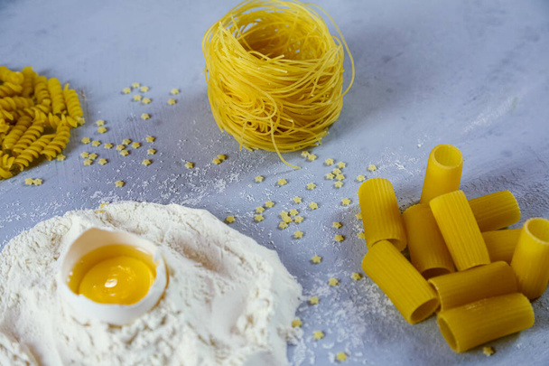 ingredients for homemade pasta. Food background: macaroni, spagetti, egg, flour - 写真・画像