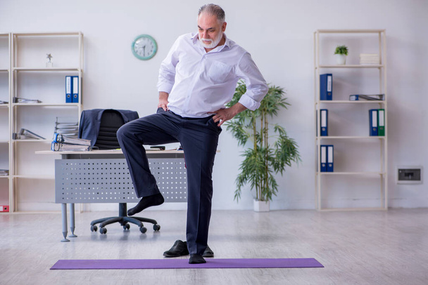 Мужчина в возрасте делает физические упражнения во время перерыва - Фото, изображение
