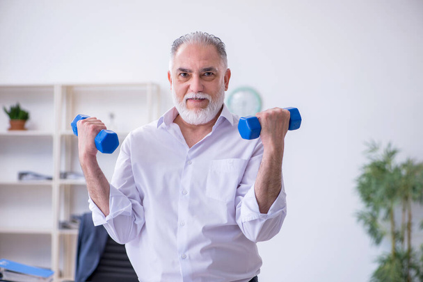 Aged male employee doing physical exercises during break - Photo, Image