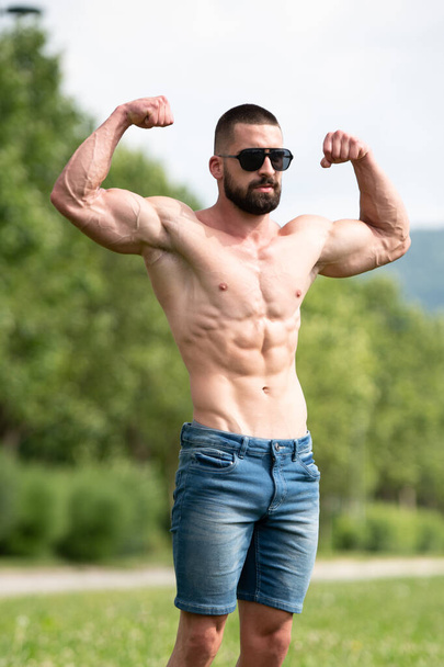 Handsome Beard Man Standing Strong and Posing at Outdoors - Background Nature of Leaves - Zdjęcie, obraz