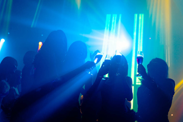 Silhouette image of people dance in disco night club to music from DJ on stage - Фото, зображення