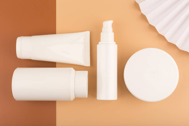 Top view of variety of cosmetic products on brown and beige background - Photo, Image