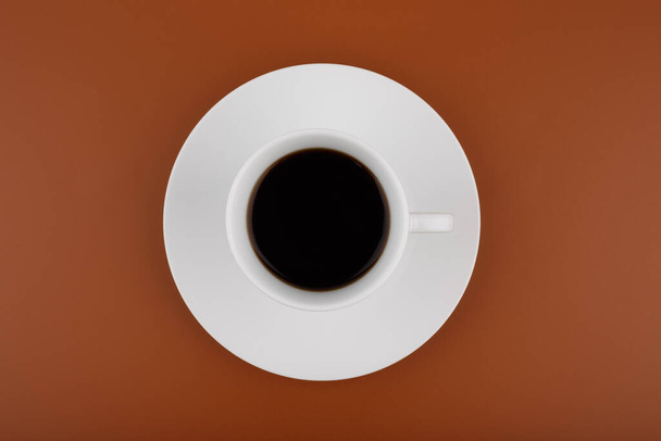 Top view of white coffee cup on a table against brown background - Foto, afbeelding