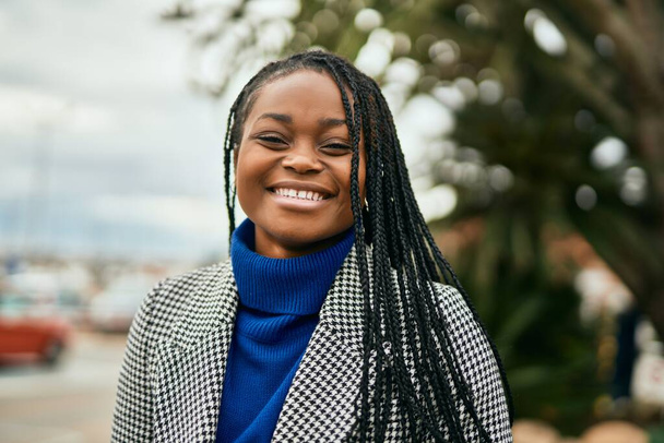 Молодая африканская американская бизнесвумен улыбается счастливо стоя в городе. - Фото, изображение