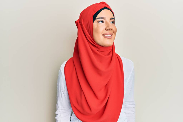 Joven chica hispana hermosa usando bufanda hijab islámica tradicional mirando hacia otro lado con sonrisa en la cara, expresión natural. riendo confiado.  - Foto, imagen
