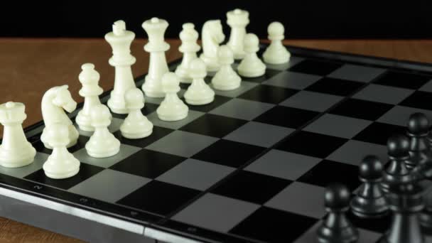 Um jogo de xadrez. A mão de um homem move uma peça de xadrez num quadro negro. - Filmagem, Vídeo