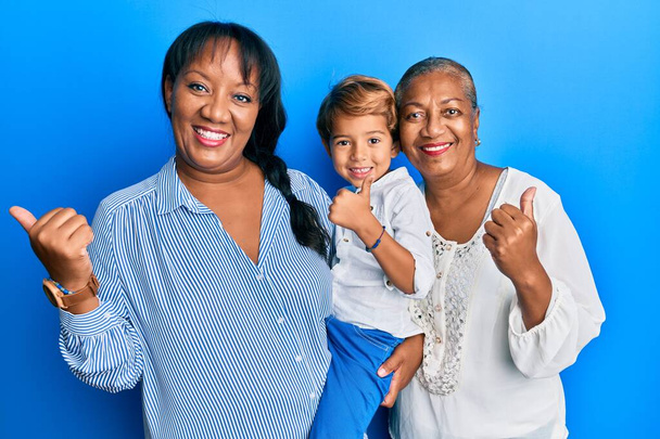 母と息子のヒスパニック系の家族一緒に手を指す親指で側に幸せな笑顔でオープン口  - 写真・画像