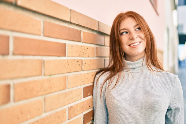 Молода ірландська дівчина-підліток посміхається щасливо спираючись на стіну в місті
. - Фото, зображення