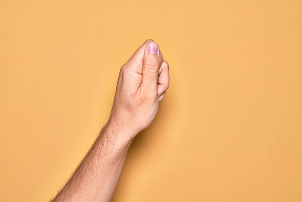 Hand of caucasian young man showing fingers over isolated yellow background holding blank space with thumb finger, business and advertising - Photo, Image