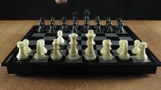 Ένα παιχνίδι σκάκι. Ένας άντρας παίζει με τον εαυτό του μετακινώντας κομμάτια σε μια μαύρη σκακιέρα. - Πλάνα, βίντεο