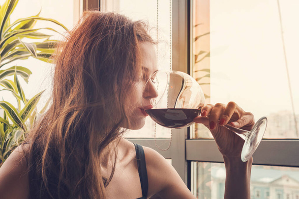 Close-up portret van jonge vrouwelijke klant die rode wijn drinkt met gesloten ogen. Vrouw die wijn drinkt, een SIP van een glas neemt. Wijnproeverij in het restaurant. - Foto, afbeelding
