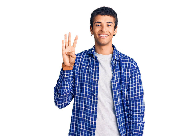 自信を持って幸せな笑顔ながら、若いアフリカ系アメリカ人の男性は、カジュアルな服を着て指の数4を示すと指摘します.  - 写真・画像