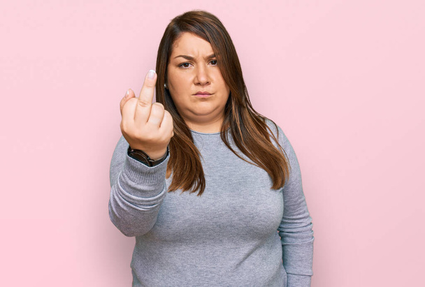 Beautiful brunette plus size woman wearing casual clothes showing middle finger, impolite and rude fuck off expression  - Foto, immagini