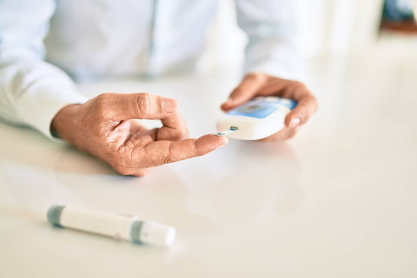 Close up of man with diabetes using insuline glucometer with blood from the finger - Fotó, kép
