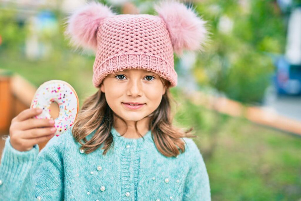 Adorável caucasiano criança menina sorrindo feliz comer donut no parque. - Foto, Imagem