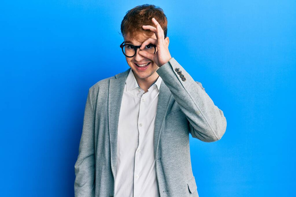 Young caucasian man wearing elegant clothes and glasses doing ok gesture with hand smiling, eye looking through fingers with happy face.  - Photo, Image