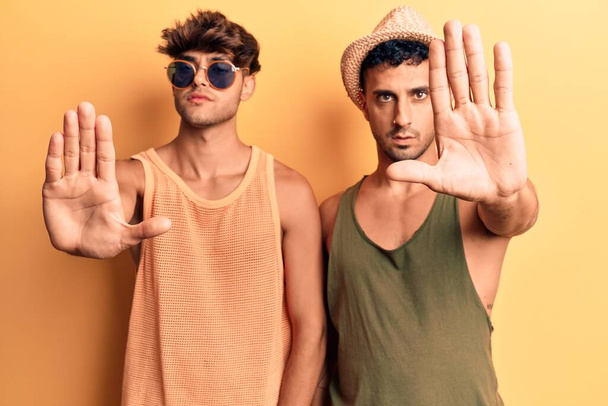 Mladý gay pár v letních šatech přestane zpívat dlaní ruky. varovný výraz s negativním a vážným gestem na tváři.  - Fotografie, Obrázek