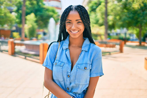 Νεαρή Αφρικάνα Αμερικανίδα χαμογελά χαρούμενη περπατώντας στο πάρκο. - Φωτογραφία, εικόνα