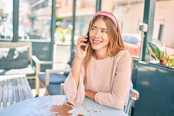 Young caucasian girl smiling happy using smartphone at the city. - Photo, image