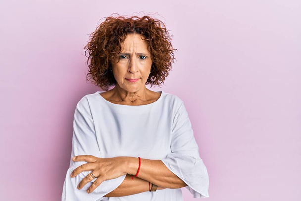 Beautiful middle age mature woman wearing elegant clothes over pink background skeptic and nervous, disapproving expression on face with crossed arms. negative person.  - Photo, Image