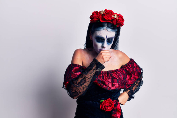 Junge Frauen, die am Tag des Todes mexikanisches Make-up tragen, fühlen sich unwohl und husten als Symptom für Erkältung oder Bronchitis. Gesundheitskonzept.  - Foto, Bild