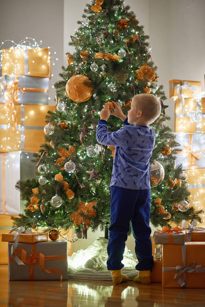Ребенок украшает елку дома ночью - Фото, изображение
