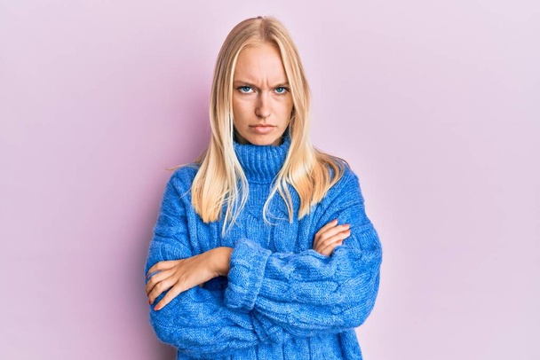 Young blonde girl wearing wool winter sweater skeptic and nervous, disapproving expression on face with crossed arms. negative person.  - Фото, зображення