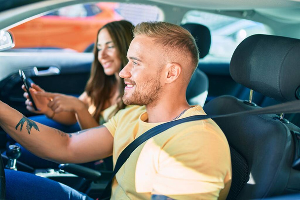 Giovane coppia sorridente felice guida auto e utilizzando gps navigatore smartphone. - Foto, immagini