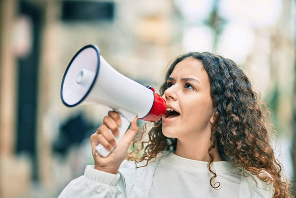 Hispanic child girl shouting angry using megaphone at the city. - Photo, Image