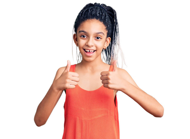 Carino afroamericano ragazza indossa abiti casual segno di successo facendo gesto positivo con la mano, pollici in su sorridente e felice. espressione allegra e gesto vincente.  - Foto, immagini