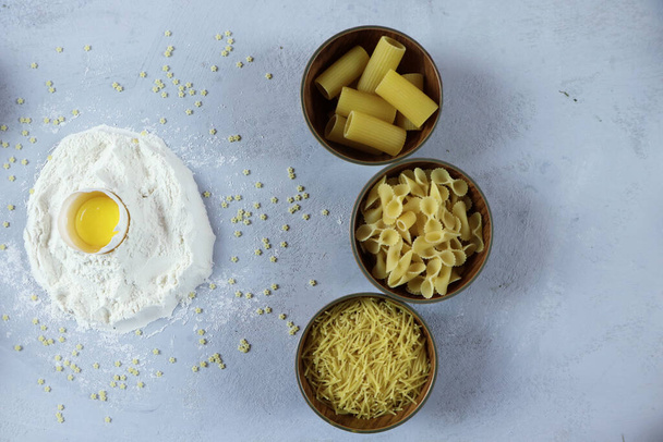 ingredients for homemade pasta. Food background: macaroni, spagetti, egg, flour - Фото, изображение