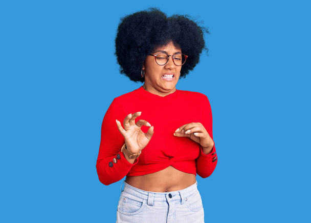 Young african american girl wearing casual clothes and glasses disgusted expression, displeased and fearful doing disgust face because aversion reaction.  - Фото, зображення