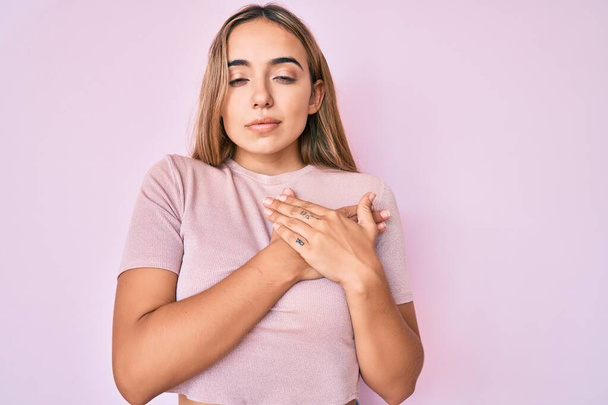 Young beautiful blonde woman wearing casual clothes smiling with hands on chest with closed eyes and grateful gesture on face. health concept.  - Photo, Image