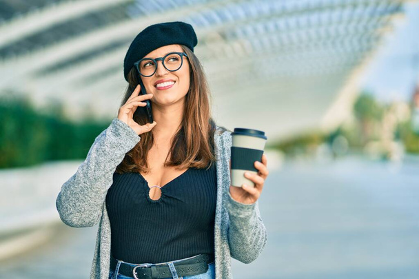 jonge latin vrouw praten op de smartphone het drinken van koffie in de stad. - Foto, afbeelding