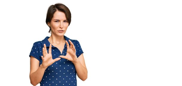 Young brunette woman with short hair wearing casual clothes disgusted expression, displeased and fearful doing disgust face because aversion reaction. with hands raised  - Photo, Image